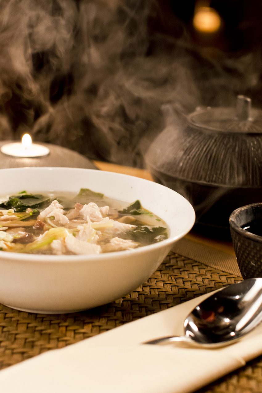 Hot chinese soup with chicken on babmboo matte.